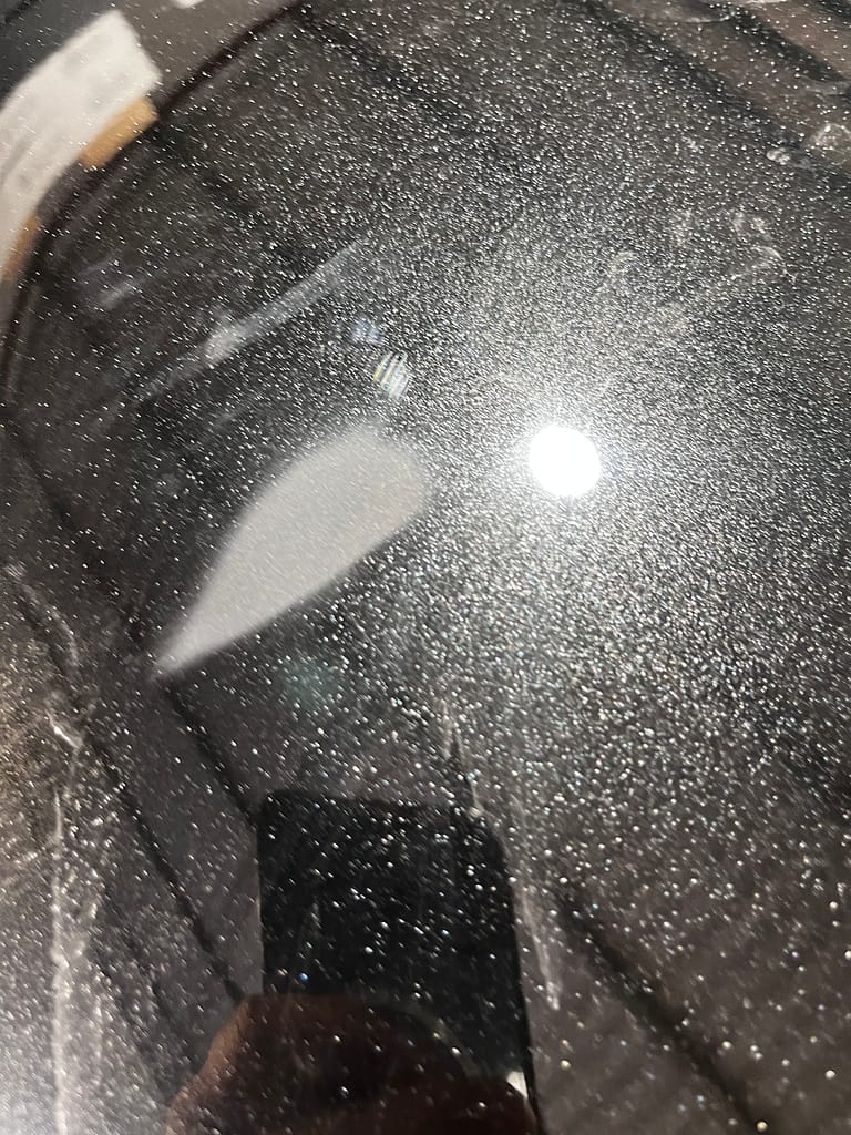 Local bonnet chip repair being refined on John's metallic-black Mitsubishi Outlander